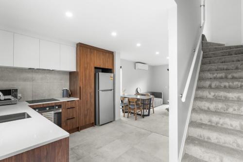 a kitchen and dining room with a staircase in a house at Sweet home near airport in Christchurch