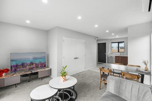 a living room with a tv and a table and chairs at Sweet home near airport in Christchurch