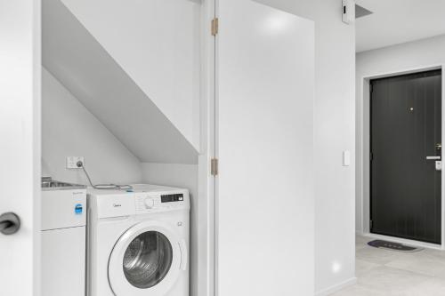 a white laundry room with a washer and dryer at Sweet home near airport in Christchurch