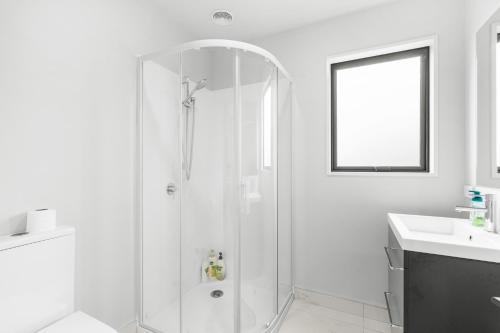 a white bathroom with a shower and a sink at Sweet home near airport in Christchurch
