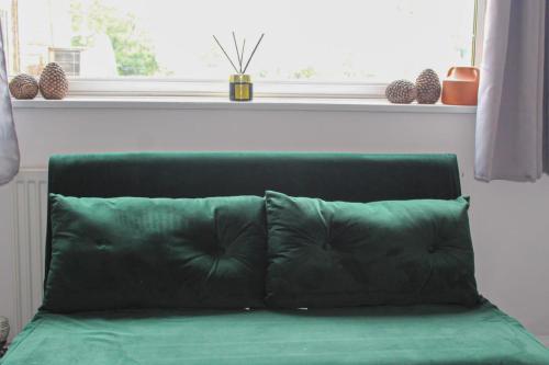 a green couch in a room with a window at SHM Stays Solihull HS2 NEC Airport Nr M6 M40 M42 Great for Long & Short stays 15 min walk to Train Station 5 min drive to Town Centre outside Bus Stops & Supermarket Free Parking in Solihull