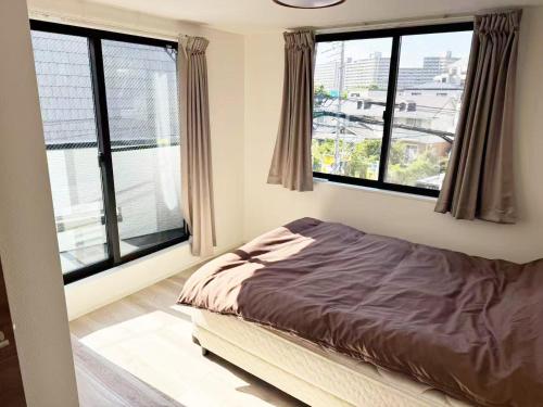 a bed in a room with large windows at Beauty House in Tokyo