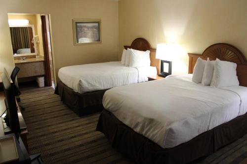 a hotel room with two beds and a television at Rodeway Inn Lynchburg near University in Lynchburg