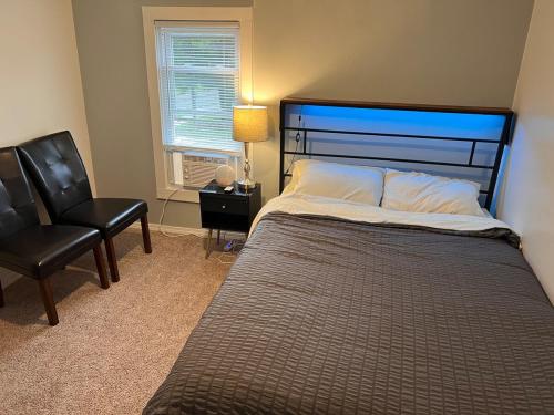 een slaapkamer met een bed, een stoel en een raam bij Finger Lakes Apartment in Hornell