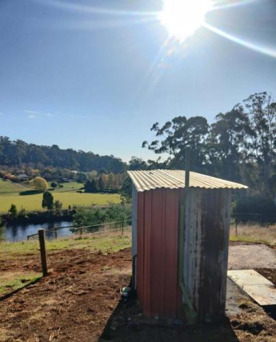 a outhouse in a field with the sun behind it at Perrys North by Tiny Away in Forth