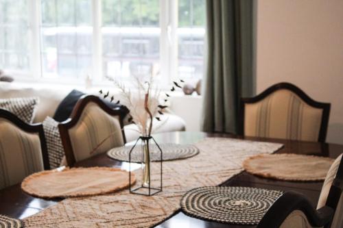 a dining room table with a vase of flowers on it at SHM Stays Solihull HS2 NEC Airport Nr M6 M40 M42 Great for Long & Short stays 15 min walk to Train Station 5 min drive to Town Centre outside Bus Stops & Supermarket Free Parking in Solihull
