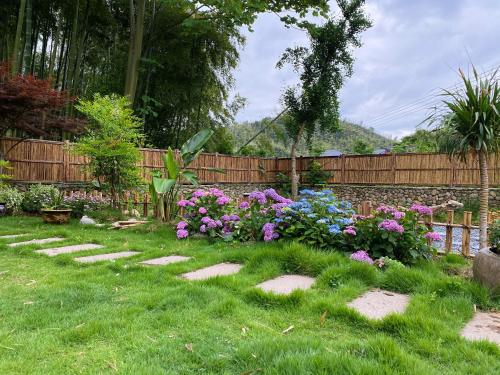 a backyard with a garden with flowers and a fence at Zhejiang Anji Xiaoshe B&B Near Zhejiang North Grand Canyon Deep Creek Canyon Rafting Jiangjunguan Rafting Wind Paragliding Zhangli Ancient Road Longwangshan Scenic Area in Shangzhang
