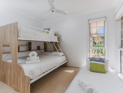a white bedroom with a bunk bed and a window at Waterfront Paradise in Tweed Heads