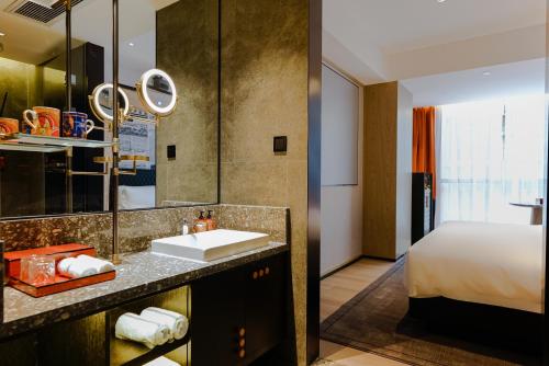 广州Arthur Hotel Baiyun Guangzhou的房间里有带水槽的浴室和一张床