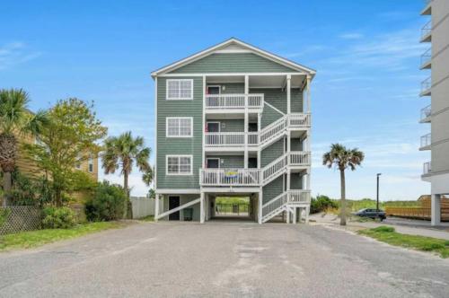 a green apartment building with a balcony and palm trees at Serenity is Yours Oceanfront Pool SP2 in Myrtle Beach