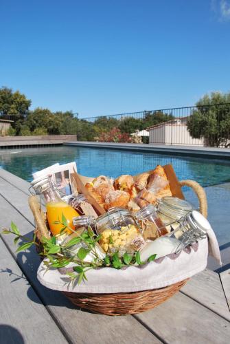 een mand met eten op een tafel naast een zwembad bij Villa Madra in Bonifacio