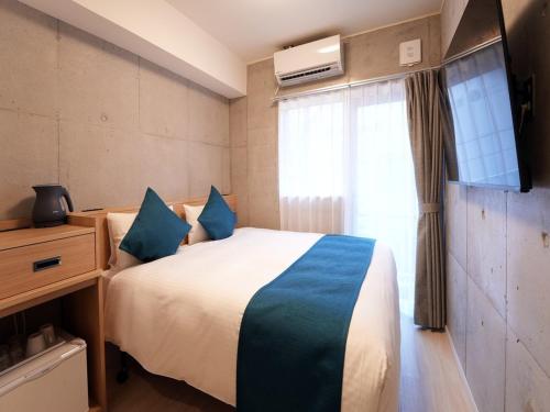 a bedroom with a bed and a tv and a window at The BREAKFAST HOTEL MARCHE Ishigaki Island in Ishigaki Island