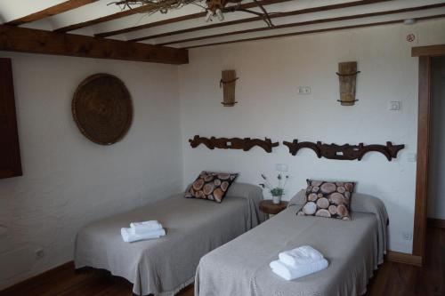 Duas camas num quarto com paredes brancas e pisos em madeira em Casa Rural Bioenergética La Serrezuela em Olmos de Atapuerca