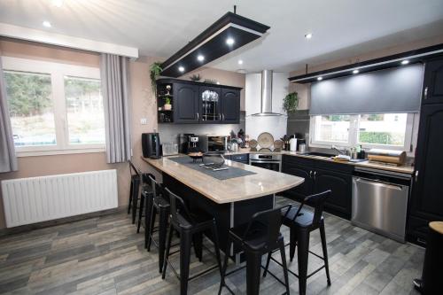 une cuisine avec des armoires noires, une table et des chaises dans l'établissement La Maison Du Bonheur, à Jarménil