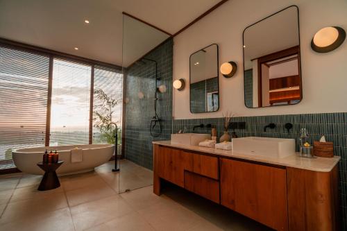 a bathroom with two sinks and a tub and mirror at Grün Resort Uluwatu in Uluwatu
