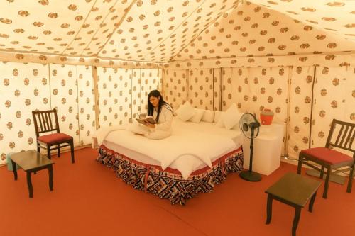 a woman sitting on a bed in a tent at Om Luxury family Resort in Jaisalmer