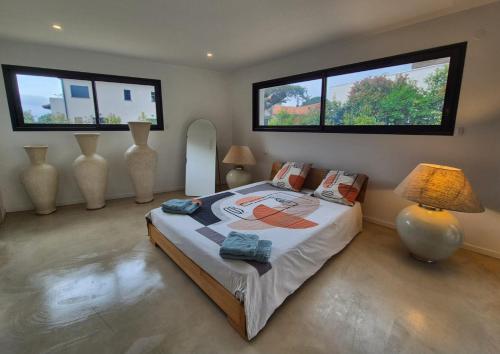 une chambre avec un grand lit avec deux fenêtres dans l'établissement VILLA PRESTIGE Les Grenadiers, à Cabestany