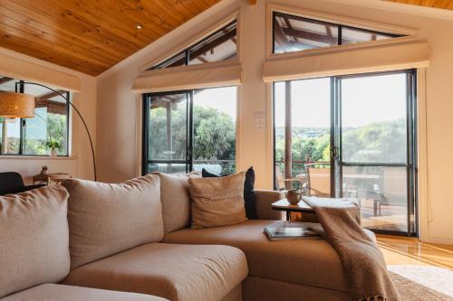 a living room with a couch and large windows at Leeuwin Rise - Gnarabup in Gnarabup