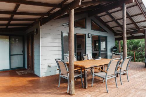 a wooden table and chairs on a deck at Leeuwin Rise - Gnarabup in Gnarabup