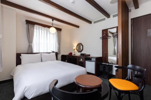 a hotel room with a bed and a table and chairs at Matsumoto Hotel Kagetsu in Matsumoto