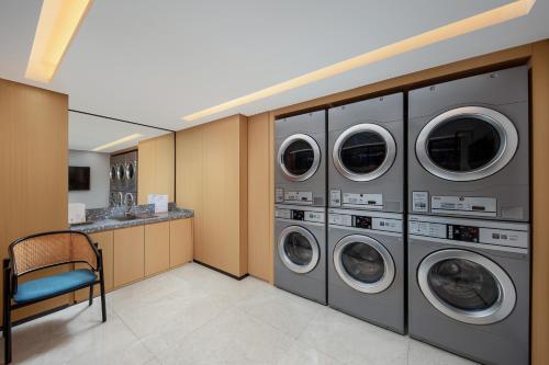 a laundry room with four washing machines and a chair at Hilton Garden Inn Shanghai Jiading in Shanghai