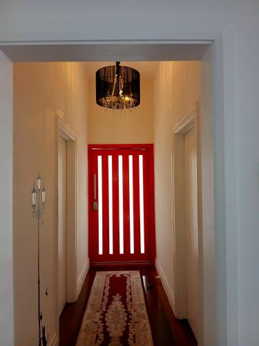 a red door in a hallway with a chandelier at Cozy and Peaceful home surrounding by cafes and restaurants in Perth