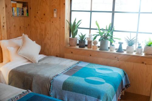 een slaapkamer met een bed en een raam met potplanten bij Batonship Inn Osaka 005 in Osaka