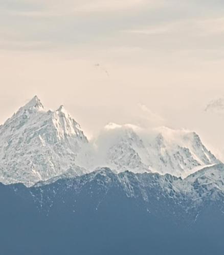 a snow covered mountain range in the distance at The Wooden Homestay By StayApart in Rishop