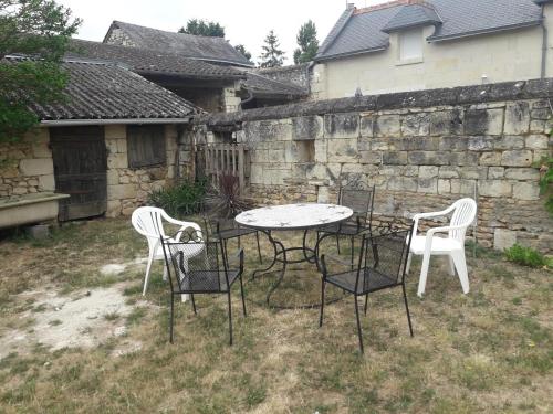 a table and chairs in a yard next to a stone wall at Maison conviviale avec jardin à Raslay, 80 m² in Raslay
