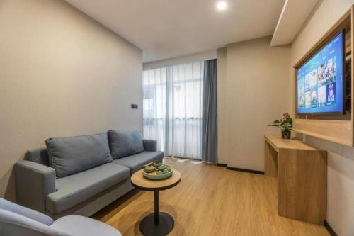 a living room with a couch and a tv at GreenTree Inn Express Zhangjiagang Hexing Town Shazhou Professional Institue of Technology in Qiwei