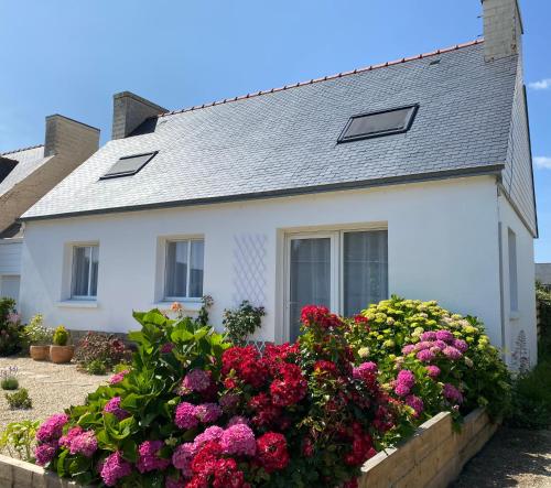 une maison blanche avec des fleurs devant elle dans l'établissement La maison de Marie, à Plovan