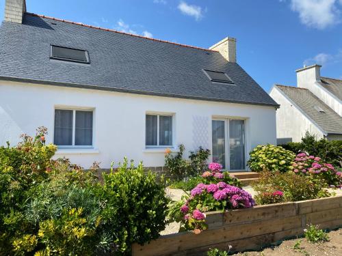 une maison blanche avec des fleurs dans un jardin dans l'établissement La maison de Marie, à Plovan