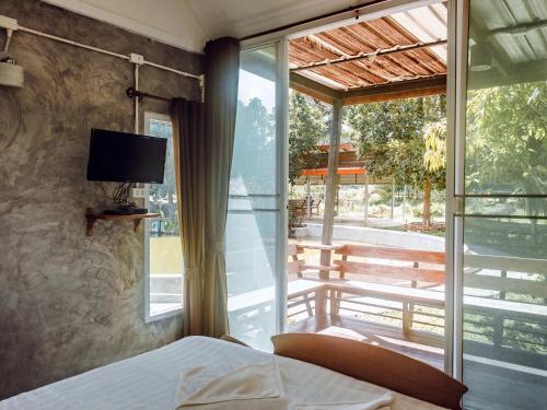 a bedroom with a bed and a window with a television at Tantai Eco Farm Stay At Khao Yai in Ban Sap Noi