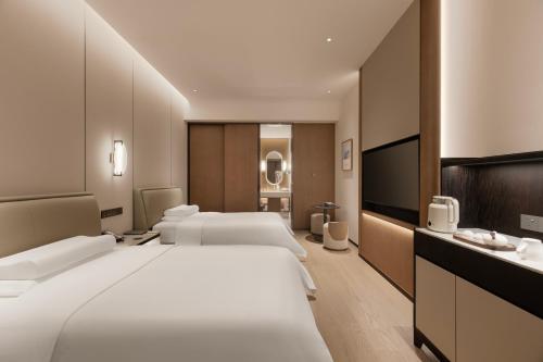 a hotel room with three beds and a flat screen tv at Mlily Hotel in Shanghai