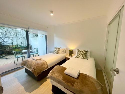 1 dormitorio con 2 camas y balcón con mesa en Jetty Blonde - Bright, Beachy & Perfectly Located, en Coffs Harbour
