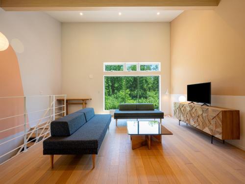a living room with a blue couch and a tv at Minn house Niseko Hirafu in Kutchan