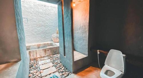 a bathroom with a toilet in a room with a window at Avartarn Miracles Hotel in Ban Soi Rakhlong