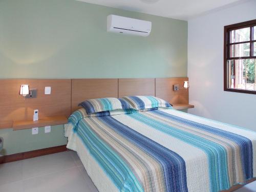 a bedroom with a bed with a striped blanket at Ancoradouro Flats in Abraão
