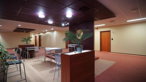 a waiting room with tables and chairs and a plant at Meriniitty Hotelli in Salo