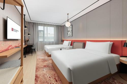 a hotel room with a large white bed and a desk at Hilton Garden Inn Shanghai Jiading in Shanghai