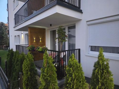 a white house with a balcony and trees at Apartament Kwiatowy DeLux in Sanok