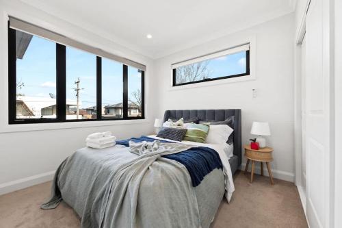 a bedroom with a bed in a room with windows at Chic 3BR House Near Box Hill in Box Hill