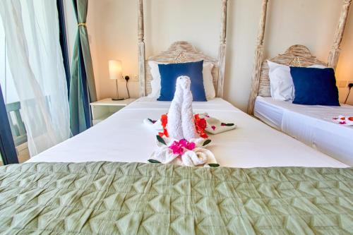 a hotel room with two beds with a stuffed animal on the bed at Diani Beachfront Villa Amani at Diani in Ukunda