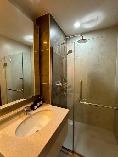 a bathroom with a sink and a glass shower at The Astra Condo, Downtown in Chiang Mai