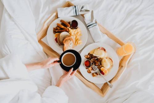 a person holding a cup of coffee and a plate of food at Plaka Hideaway Suite in Athens