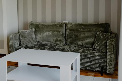 a living room with a couch and a white table at Dandzenieki in Pāvilosta