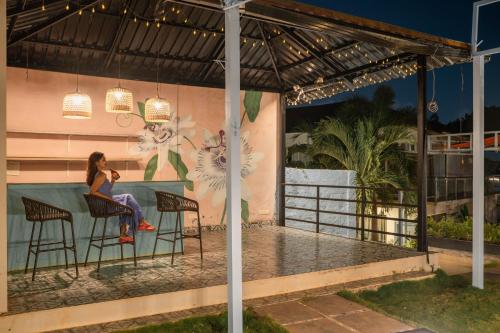 a woman sitting at a bar in front of a wall at Koko Maya by Perfectstayz near Morjim Beach in Morjim
