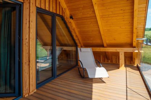 a white chair sitting on a porch of a wooden house at Domki Na Wspólnej in Wisła