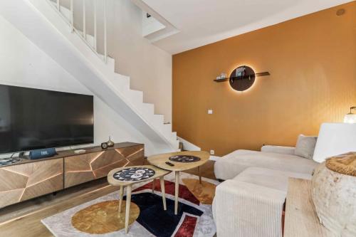 un salon avec un canapé et une télévision dans l'établissement Le Malicieux, à Paris