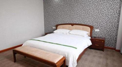 a bedroom with a bed and a bench in it at GreenTree Inn Gaoyou Government in Yangzhou